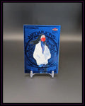 Blaue Medaillons Trading Card mit Frau in weißer Jacke und rotem Mundschutz, auf Ständer