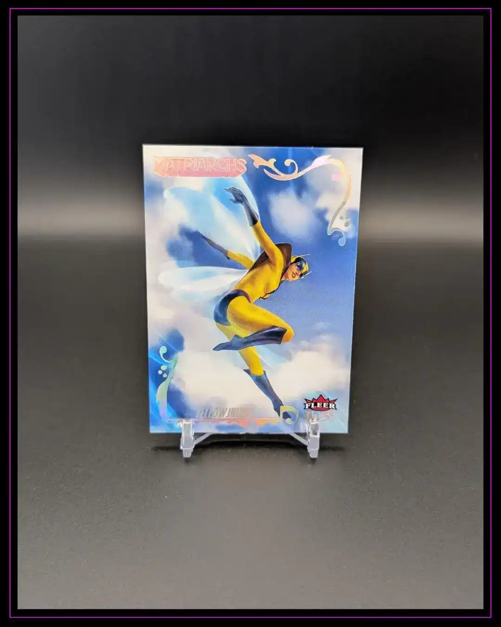 Trading Card mit Comic-Heldin in gelbem Kostüm, dynamischer Pose, Wolkenhintergrund, Fleer-Logo