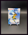 Trading Card mit Comic-Heldin in gelbem Kostüm, dynamischer Pose, Wolkenhintergrund, Fleer-Logo