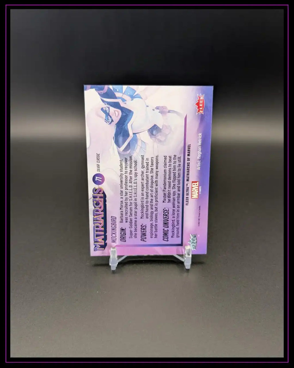 Rückseite einer Trading Card mit Superheldinnen-Illustration und Beschreibung auf Kartenständer