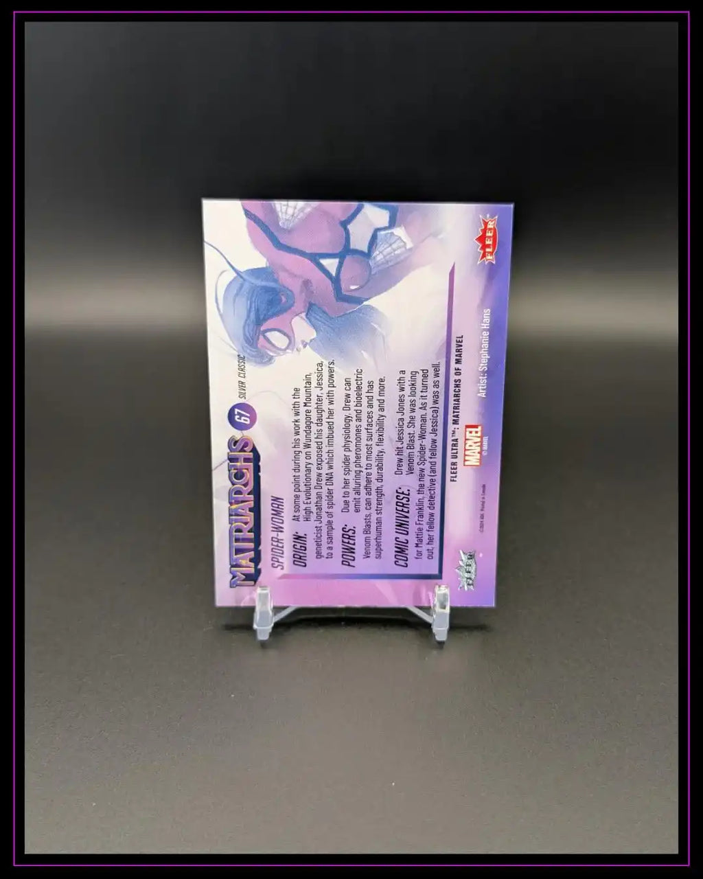Rückseite einer Marvel Trading Card mit Spider-Woman Illustration und Kartendetails auf Ständer