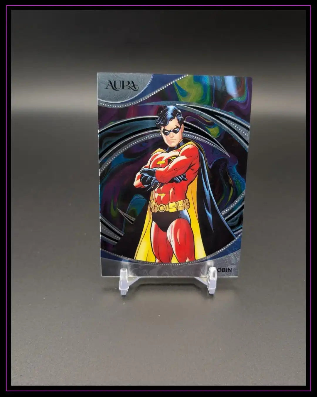 Trading Card mit Comic-Held in rotem Kostüm auf Ständer, bunte Aura-Hintergrundgrafik