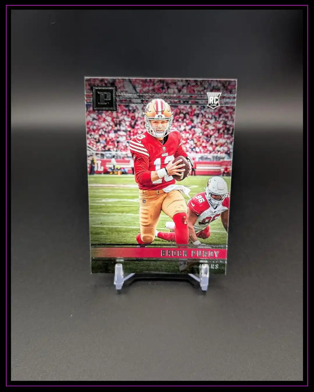 Football Rookie Trading Card mit Spieler im rot-goldenen Trikot auf schwarzem Ständer